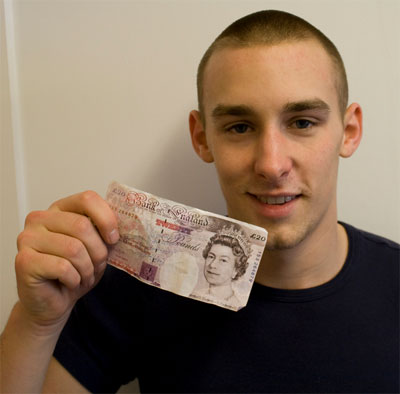 Молодой дизайнер Рикки Ричардс показывает свою визитку, похожую на 20-фунтовую банкноту